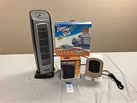 Wide shot showing Lasko tower fan, Ziploc space bags box, Duracraft ceramic heater in box, and Blaux personal heater.