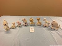 Full set of Precious Moments Birthday Series figurines: clown leader, baby bear 'For Baby', and numbers 3, 4, 5, 7, 9, 10 in pastel colors, mounted on wheels.