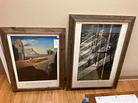 Two Salvador Dali Museum framed posters leaning against a wall, showing both posters and their cedar wood frames.
