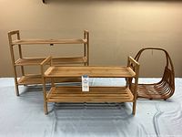 Two wooden shoe shelves of different sizes side by side on a table with a vintage rattan basket beside them.