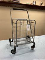 Overall view of the lightweight collapsible utility cart, showing the wire basket, handlebar, and four wheels.