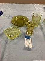 Overall lot view showing all six vintage canary glass items on a blue cloth background.