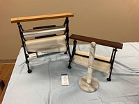 Front view of all three kitchen roll holders showing the 3-tier cast iron holder, single-tier cast iron holder, and marble paper towel holder on a cloth surface.
