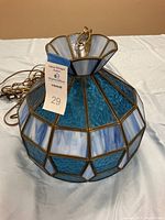Side view of vintage stained glass lamp showing geometric panel blue and white glass with brass-tone framing and hanging chain