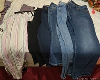 Photo of six pairs of bottoms laid flat: striped lounge pants, black trousers, and four pairs of Torrid denim jeans in various washes.