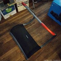 Sit-up machine with padded backrest and red handlebar on wooden floor