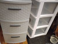 Photo of one grey and four white three drawer plastic storage units showing textures and drawer design