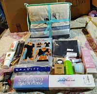 Photo showing king duvet cover set, diamond painting kit, weighted eye mask, beauty products, and health supplements spread on bed