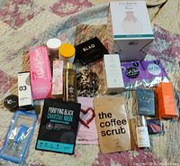 Photo showing assorted brand new makeup, masks, skincare, and beauty accessories on a quilted textile surface.