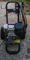 Front view showing Honda engine, pump assembly, handle, and wheels on the pressure washer.