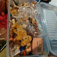 Close-up of clear plastic container holding multiple small teddy bear rubber stamps and other small craft items, some sealed in plastic bags.