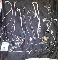 Full view of all sterling silver jewelry and pearl pieces on black cloth showing necklaces, rings, pendants, and brooch