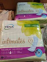 Photo of two packages of Tena Intimates bladder pads, each 39-count with maximum absorbency and fresh & clean scent.