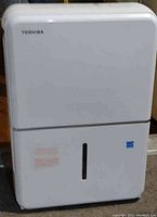 Front view of white Toshiba dehumidifier showing water level indicator.