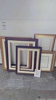 6 assorted picture frames arranged against a white wall, showing size and style variety