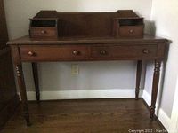 Front view of antique solid wood writing table with four drawers and two cubbies, spindle legs with spiral details visible