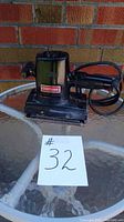 Black Craftsman sander on glass table in front of brick wall, with number 32 card.