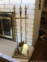 Full view of the four-piece fireplace cleaning set including stand, poker, brush, and shovel placed near fireplace.