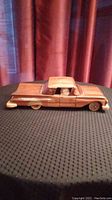 Side view of handcrafted wooden Chevrolet Impala replica showing profile and details like wheels and car body shape.