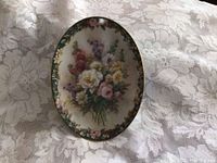 Oval floral collector plate with detailed flowers on lace background
