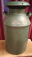 Full frontal view of the green painted vintage milk can with lid and handles.