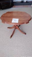 Photo of the vintage hardwood occasional table showing scalloped edges and tripod base with three curved legs.