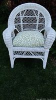 Front view of white wicker chair with the patterned cushion in place on a lawn.