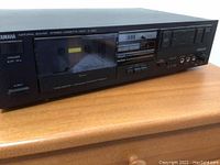 Front view of Yamaha K-320 cassette deck with locked cassette tray and visible buttons and ports.