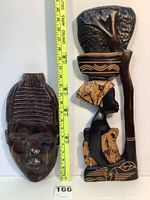 Side view showing both African wood carvings together with measuring tape indicating dimensions.