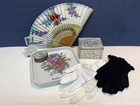 All vanity items displayed together including the gloves, cut glass jewelry box, snuff box, vanity tray, and hand fan.