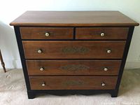 Front view of the Hitchcock dresser showing wood drawer fronts, black frame, and brass ceramic knobs.