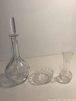 Clear glass Orrefors decanter with stopper, Dublin bud vase, and small glass bowl on table