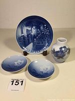Full view of Royal Copenhagen Christmas plate, two small flower motif dishes, and bud vase in blue and white porcelain.