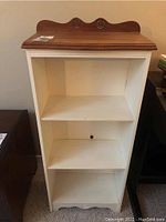 Front view of the small white composite bookshelf with wood top and three shelves