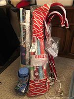 Full view of the lot showing rolls of Christmas gift wrap secured in plastic, candy cane plug-in lights with attached power cords, and several gift tins stacked at the bottom.
