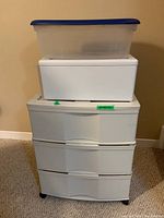 Full view of the stacked organizer set showing the white 3-drawer plastic unit with two additional containers on top, including a clear tote with a blue lid.