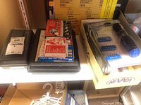 Photo showing socket wrench set with bits and packages of staples and related items in black case and white boxes