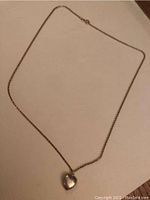 Full view of 14k gold chain necklace with heart pendant laid flat.