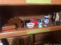Shelf view of assorted jewellery boxes, tiny figurines including a Hoselton goose sculpture, small vases and trinket boxes