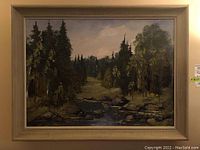 Close-up of the framed woodland landscape painting showing trees, a river, and rocks with detailed tree foliage and sky.