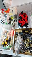 Overview of multiple plastic totes filled with mixed hardware including straps, cables, and various small items
