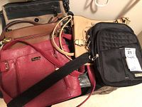 Five purses stacked showing variety of colors and styles including Fiorelli brand on the red purse