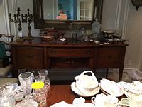Front view of the vintage wooden buffet showing four doors, a central drawer, and several decorative items placed on top.