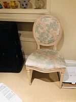 Photo of a single pickled pine wooden chair with floral upholstery on seat and backrest. Worn condition visible.