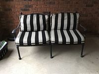 Front view of two-seat metal outdoor loveseat with black and white striped cushions