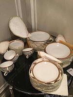 Overall view of china dinnerware set with plates, cups, saucers, and fabric-covered cases packed with tissue.