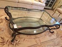 Full view of custom coffee table showing rectangular wavy glass top and circular bottom glass shelf with metal frame and curved supports.