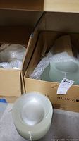 Two cardboard boxes filled with various glass dishes including bowls and plates, some wrapped in bubble wrap for protection.