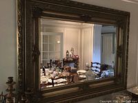 Full view of the large rectangular mirror showing the wood carved frame and room reflection.