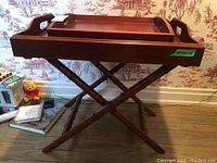 Photo showing front angle of wooden table with two trays and crossed legs resembling bamboo design.